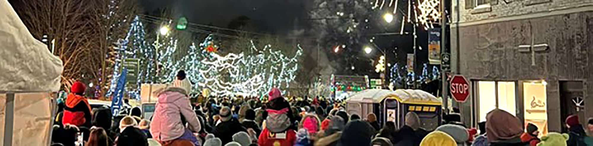 Crowd at festive holiday street parade with fireworks and lights