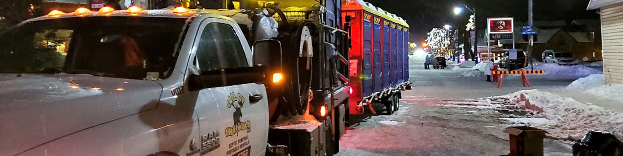 Downtown street with snow clearing vehicle at night