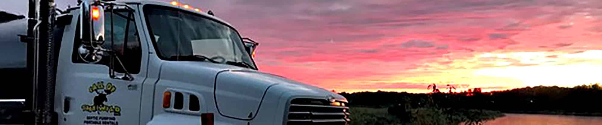 Truck parked by serene lake at vibrant sunset