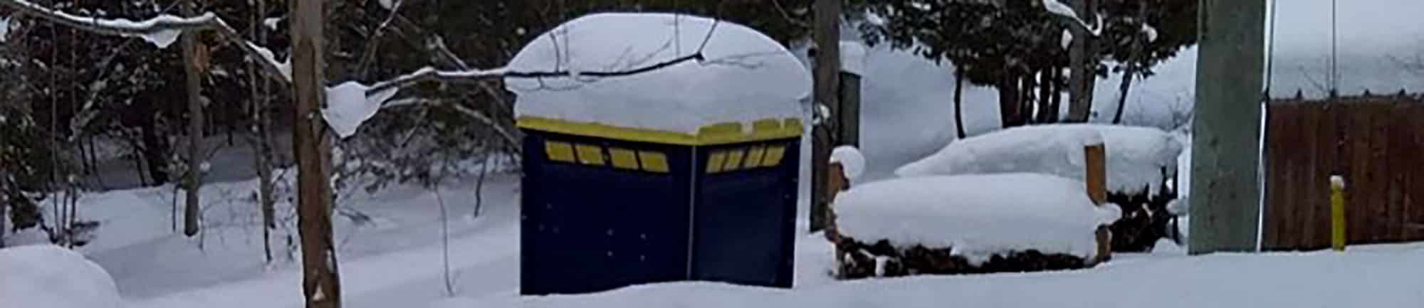 Snow-covered replica of blue time machine in winter forest