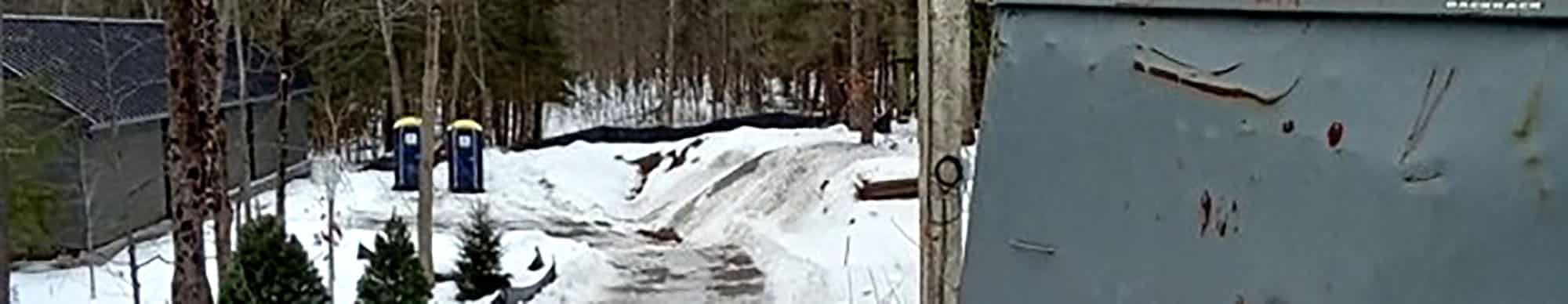 Snowy forest construction site with temporary toilets and metal barrier