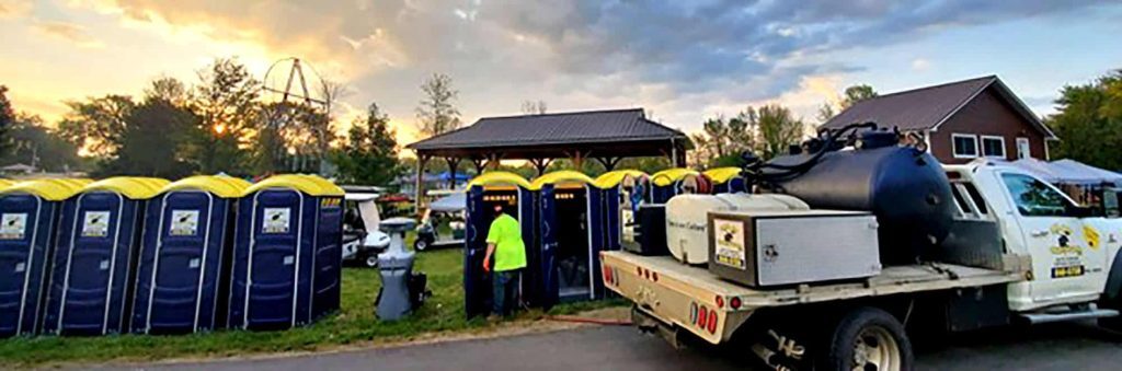Outdoor event with portable toilets and sanitation truck at sunset