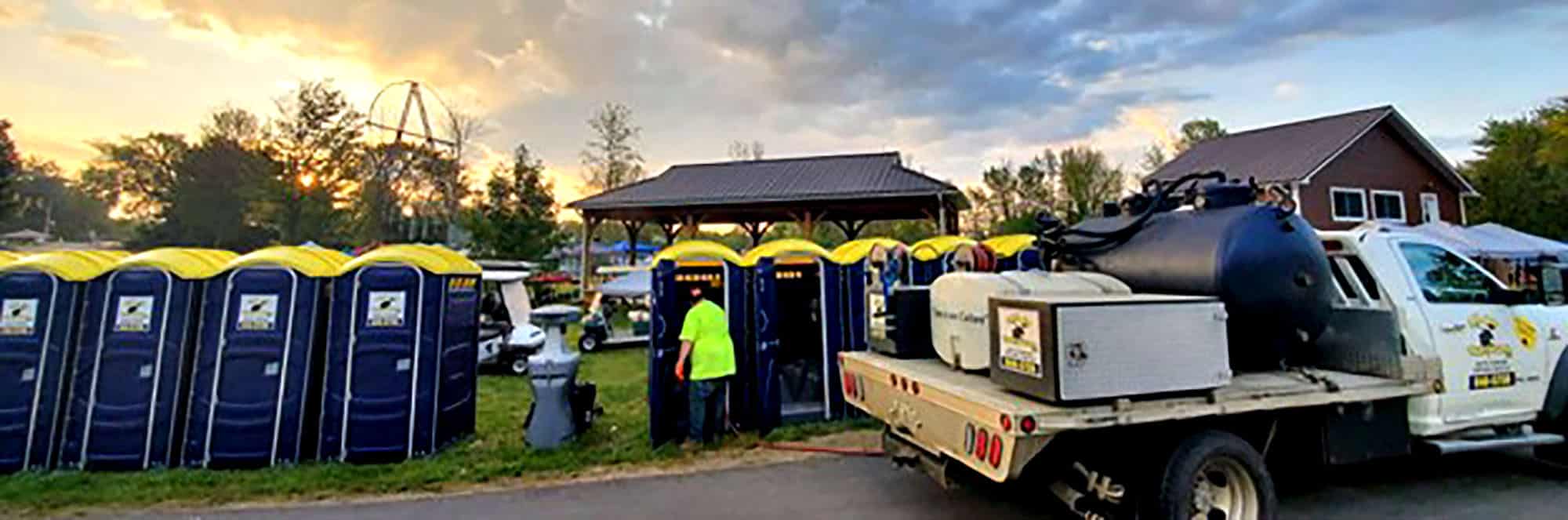 Outdoor event with portable toilets and sanitation truck at sunset