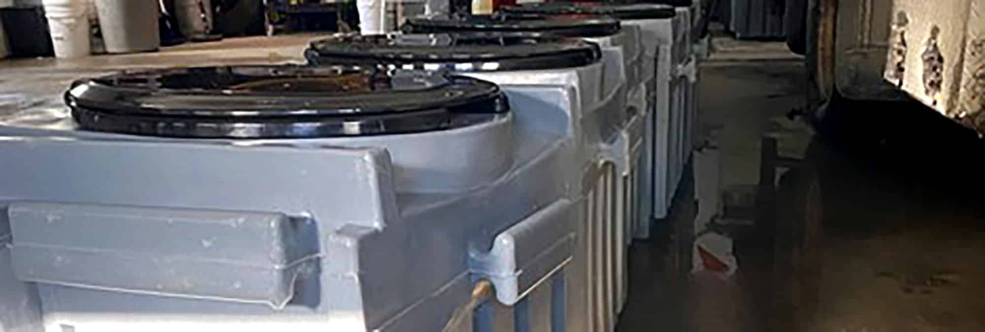 Battered grey bins in a facility with puddles