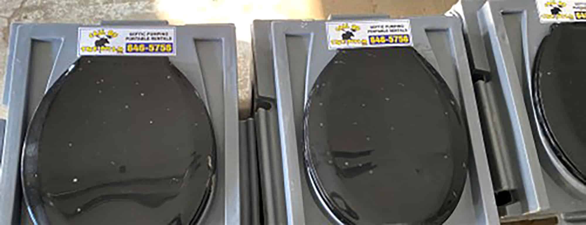 Stacked black toilet seats with contact labels in warehouse