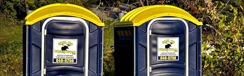 Two portable toilets with yellow roofs in a forest setting