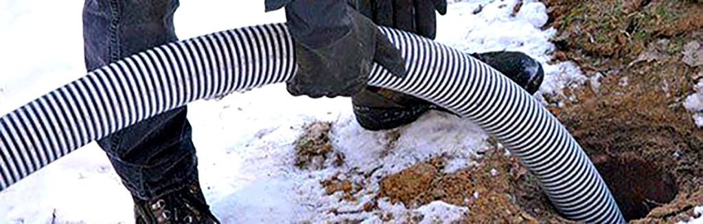 Person using a drainage pipe in snowy ground