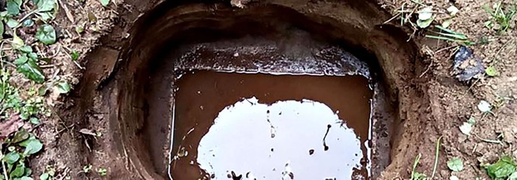Water-filled hole in the ground surrounded by soil