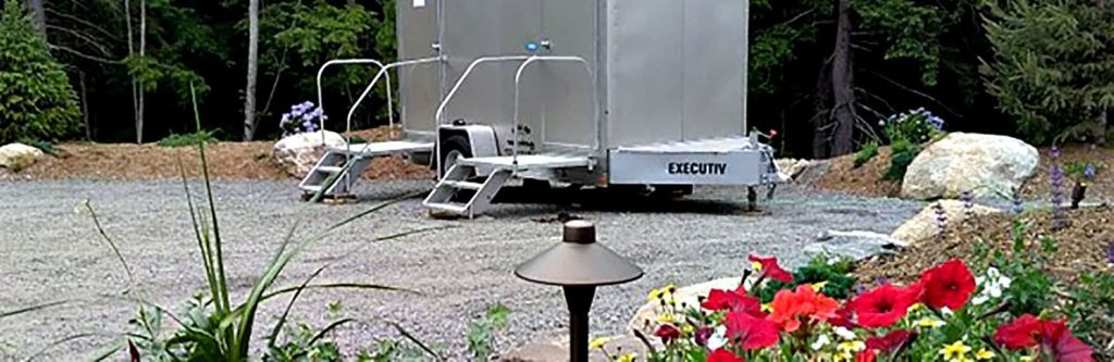 Luxury portable restroom trailer in a serene wooded setting