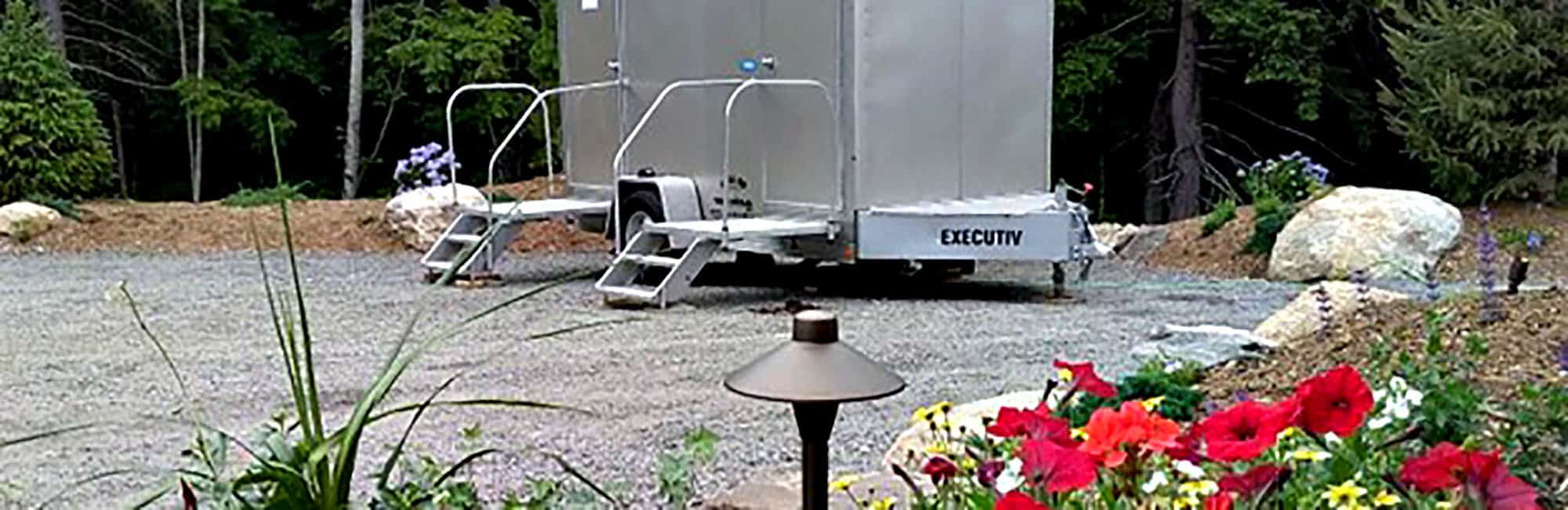 Luxury portable restroom trailer in a serene wooded setting