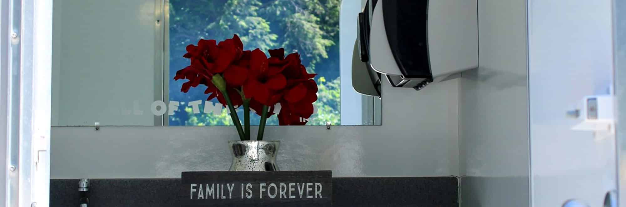 Bathroom decor featuring red flowers and 'Family is Forever' sign
