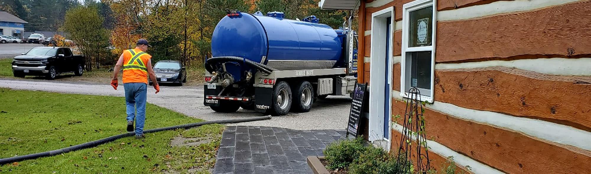 Septic tank truck servicing log cabin in rural area