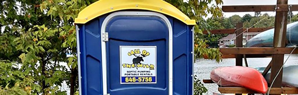 Portable toilet rental by a lake with visible canoes and trees